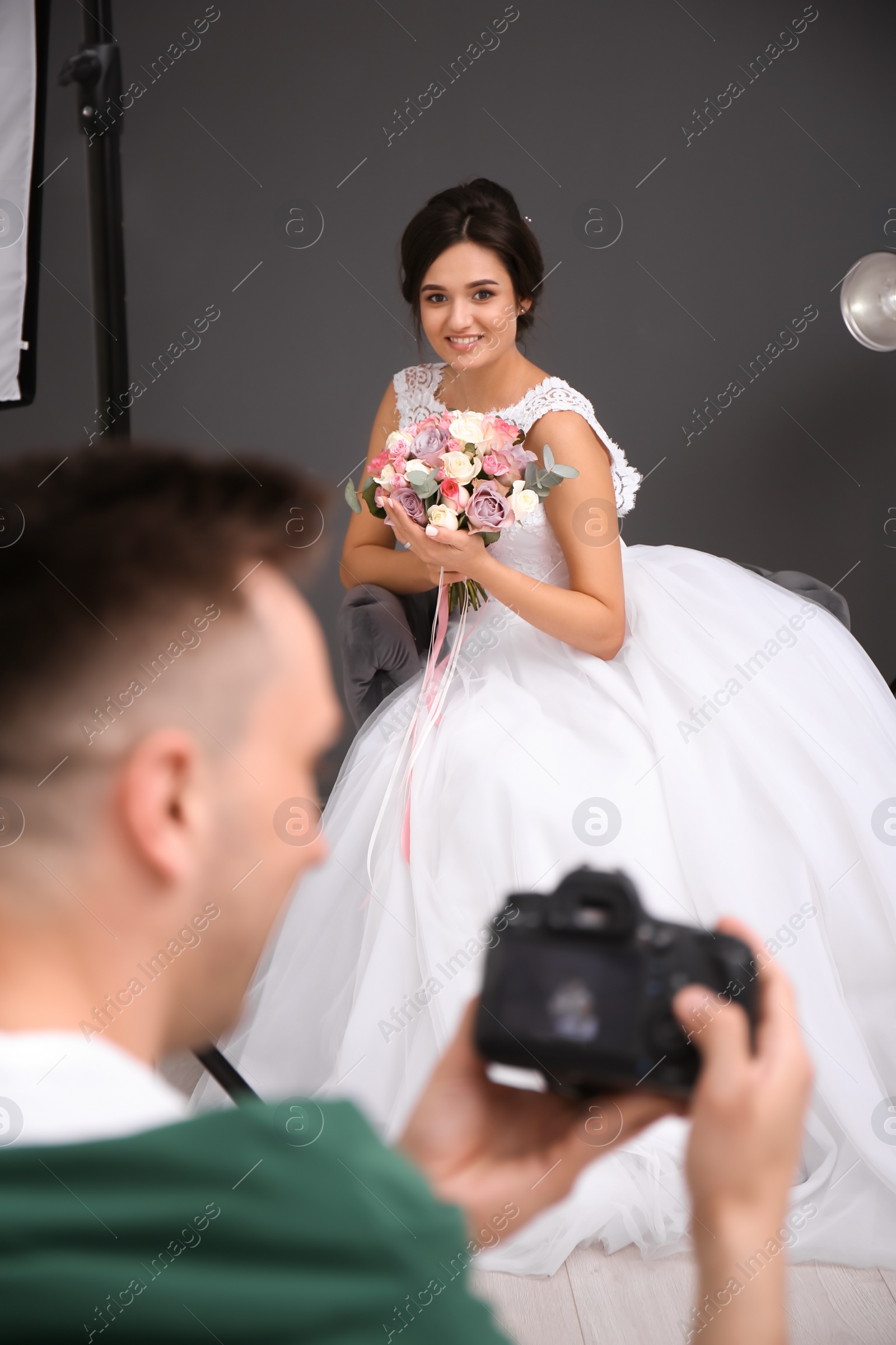 Photo of Beautiful bride and professional photographer with camera in studio
