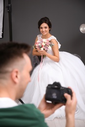 Beautiful bride and professional photographer with camera in studio