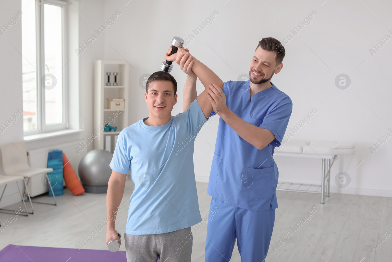 Photo of Physiotherapist working with male patient in clinic