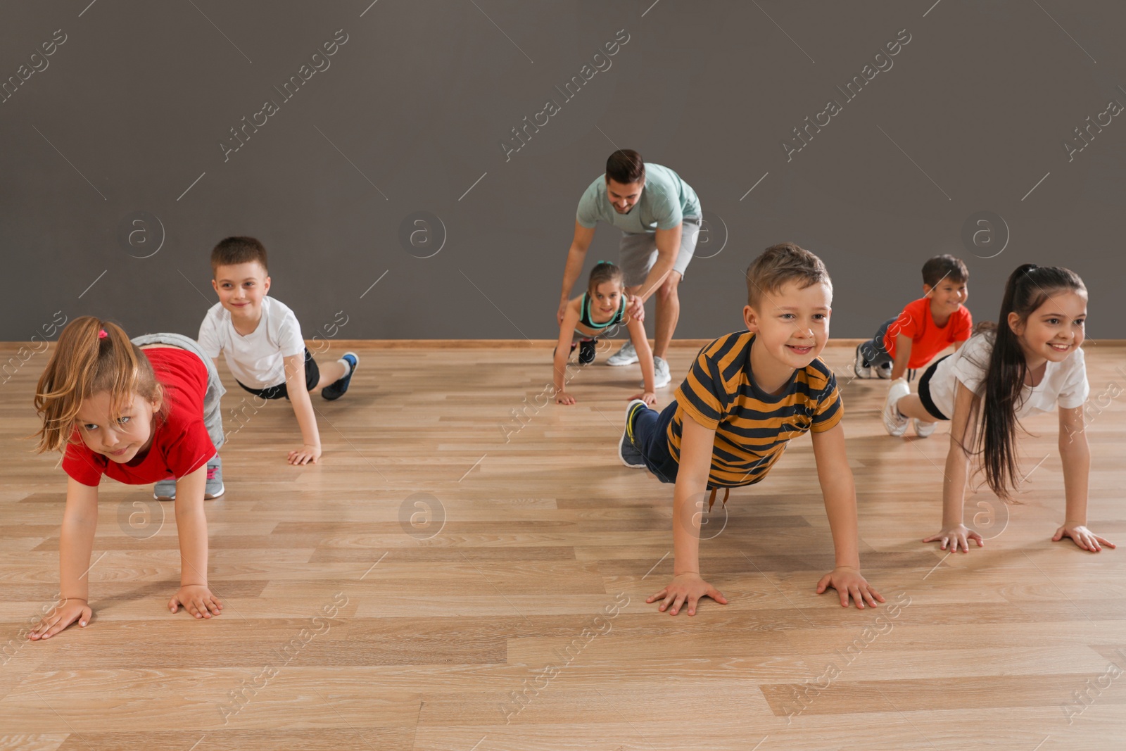 Photo of Cute little children and trainer doing physical exercise in school gym. Healthy lifestyle