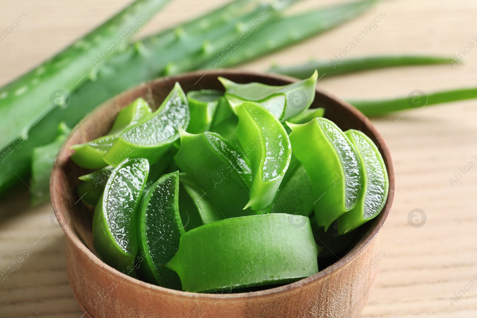 Photo of Bowl with sliced aloe vera leaves on table, closeup