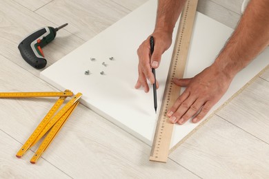 Photo of Man making mark on white board indoors, closeup. Furniture assembly
