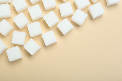 Photo of White sugar cubes on beige background, top view. Space for text