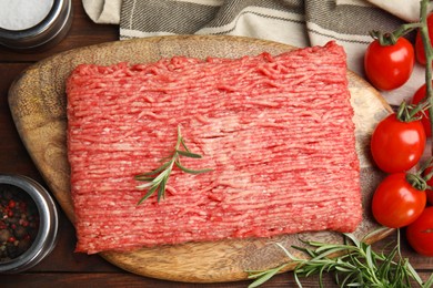 Photo of Raw fresh minced meat, tomatoes and other ingredients on wooden table, flat lay