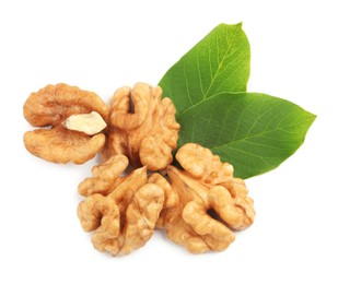Pile of peeled walnuts and leaves on white background, top view