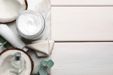 Photo of Different hand care cosmetic products, coconut pieces and eucalyptus branches on white wooden table, top view. Space for text