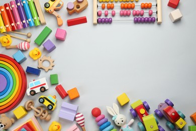 Photo of Frame of different children's toys on light grey background, flat lay. Space for text