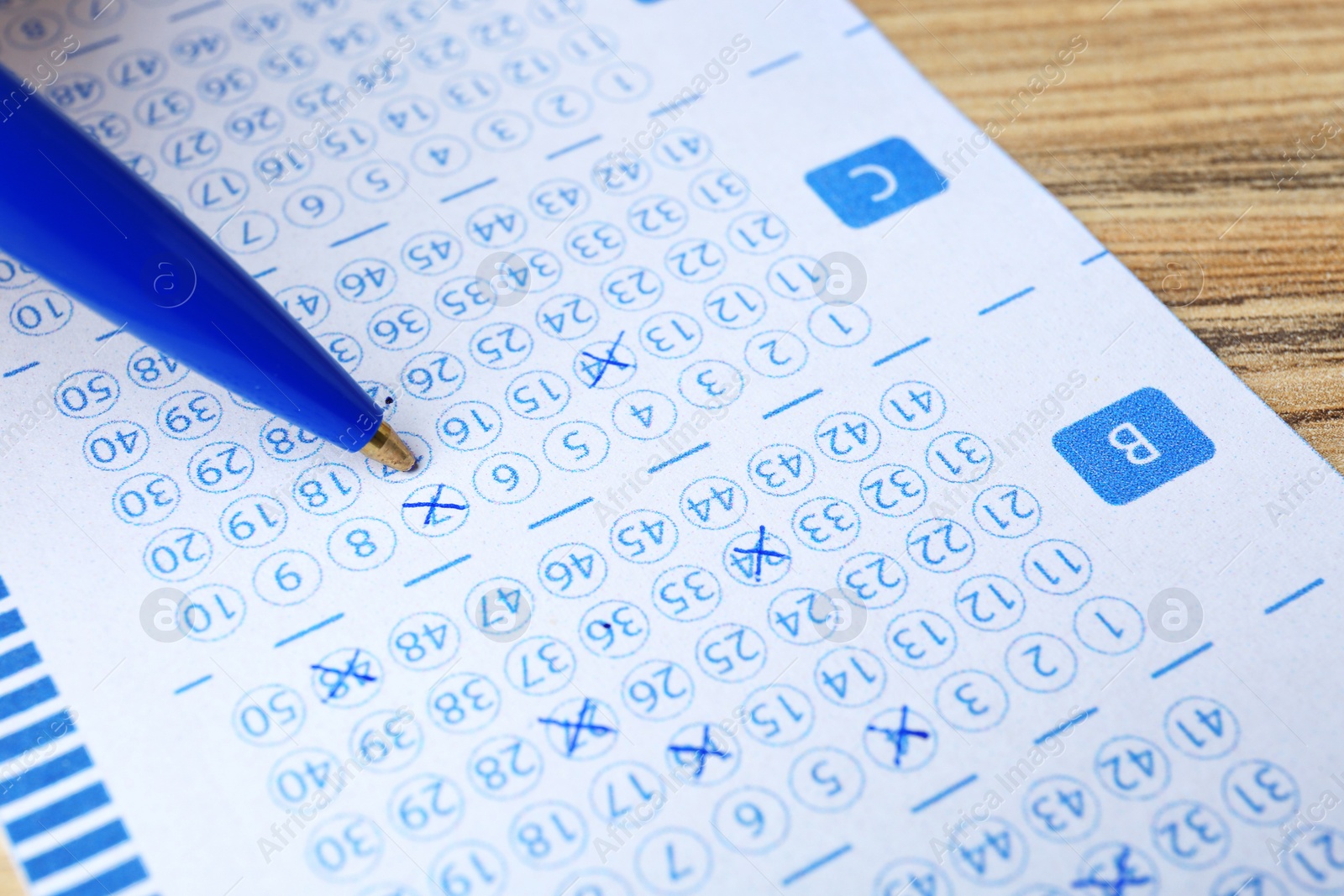 Photo of Filling out lottery ticket with pen on wooden table, closeup. Space for text