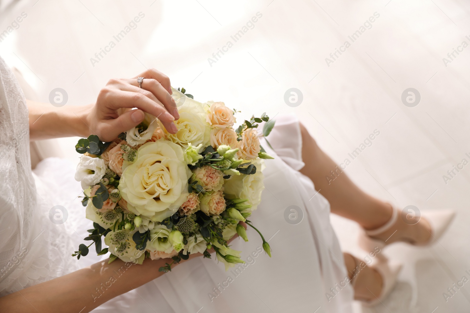 Photo of Young bride with beautiful wedding bouquet in room, above view