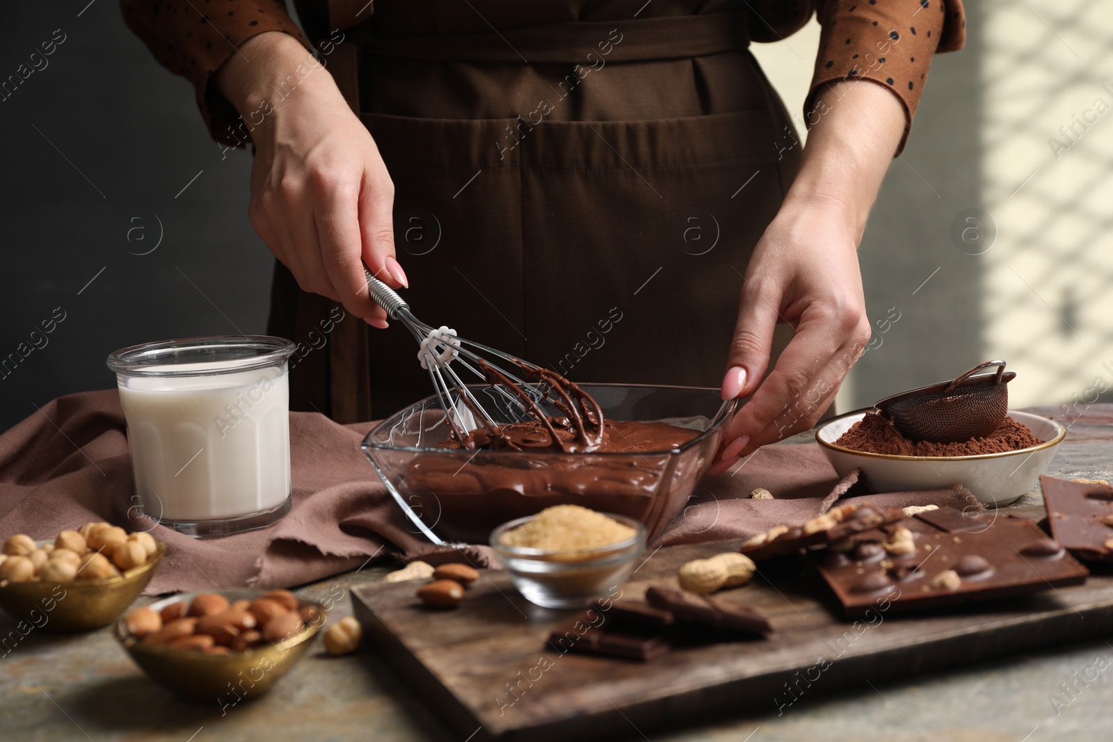 Photo of Woman mixing delicious chocolate cream with whisk at table, closeup