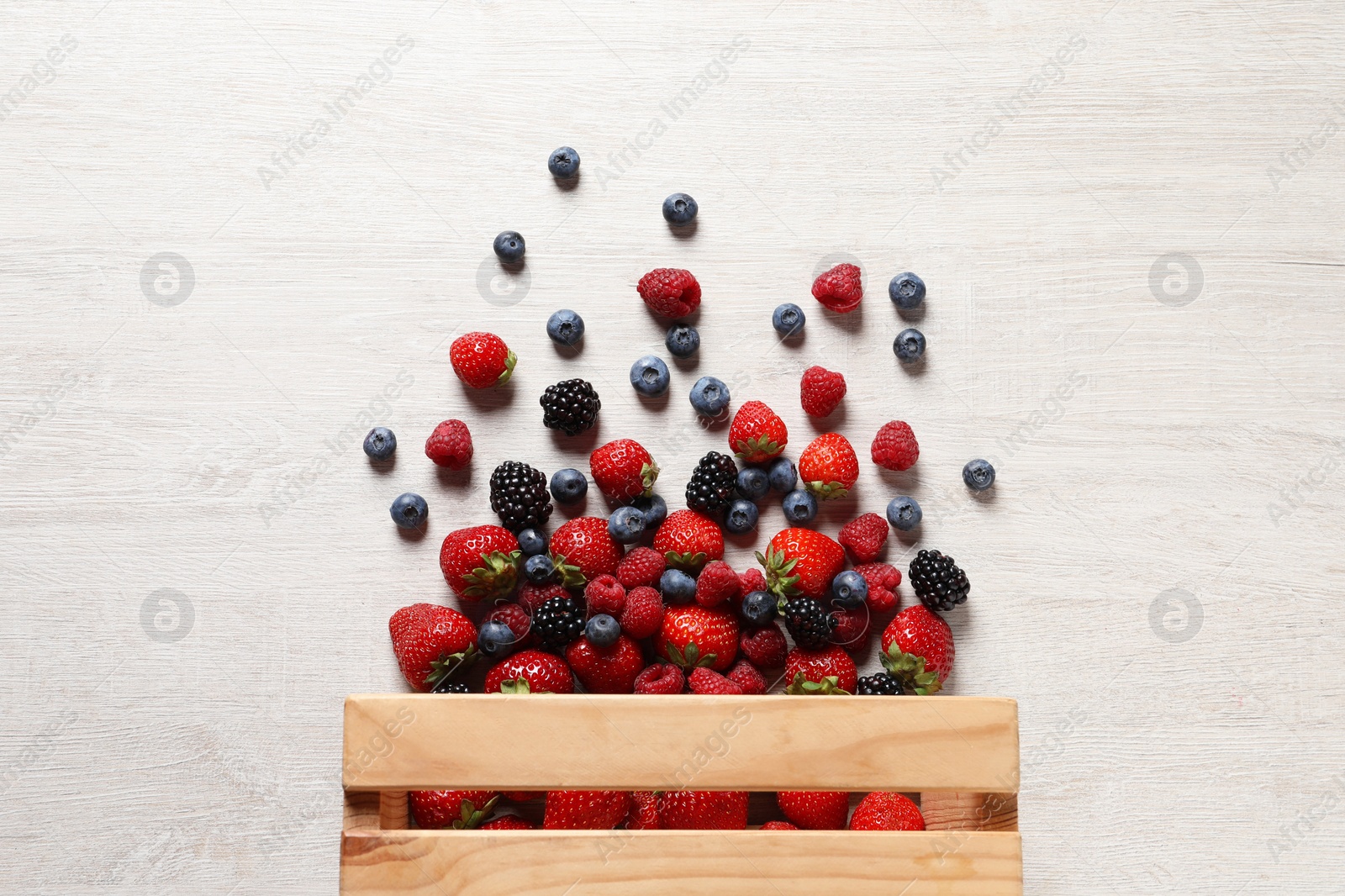 Photo of Different fresh ripe berries on light wooden table, flat lay