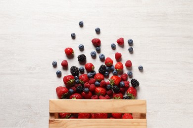 Different fresh ripe berries on light wooden table, flat lay