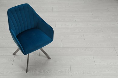 Photo of Stylish blue armchair on floor. Space for text