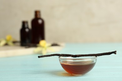 Photo of Aromatic homemade vanilla extract on light blue wooden table. Space for text