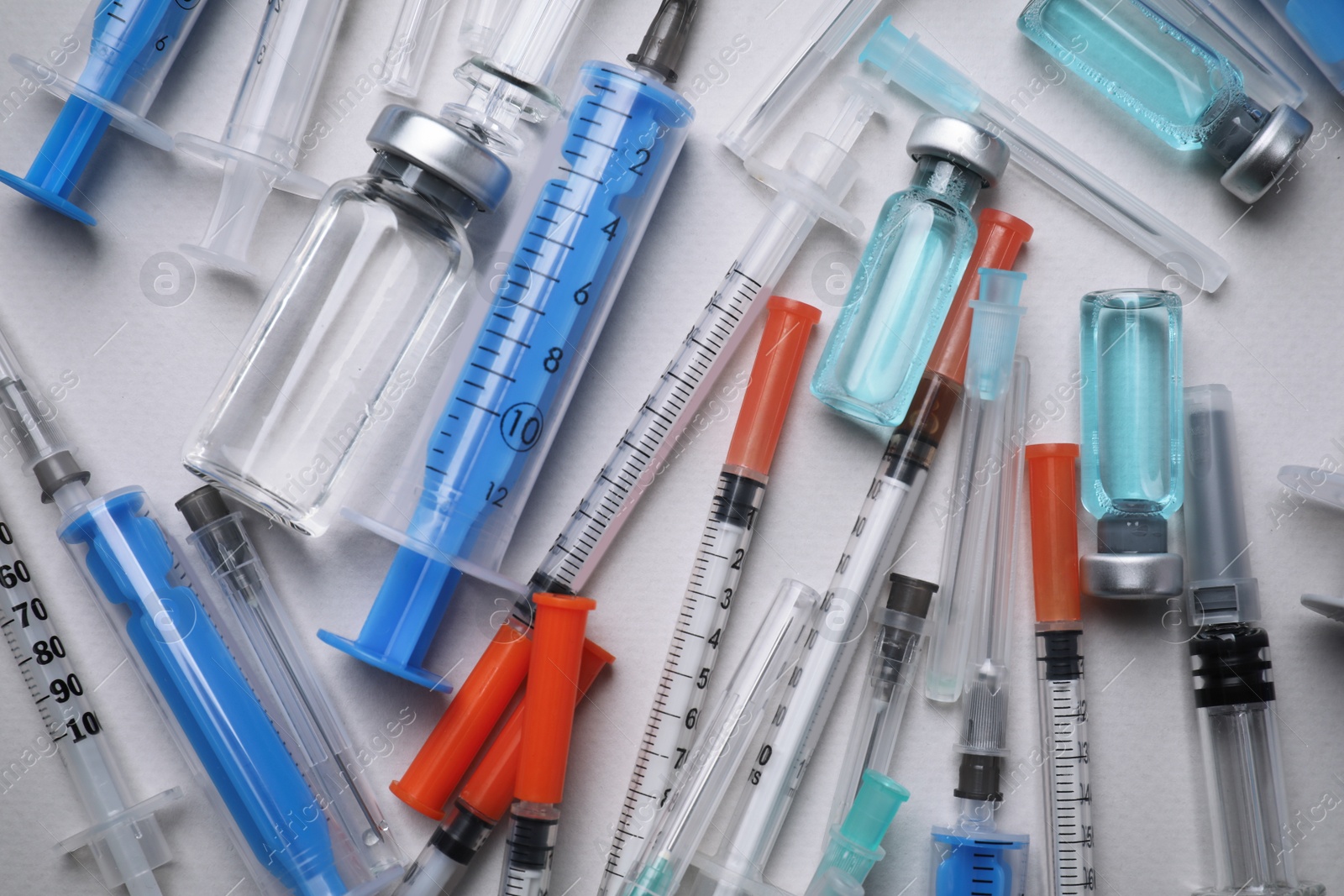 Photo of Disposable syringes with needles and vials on grey background, flat lay