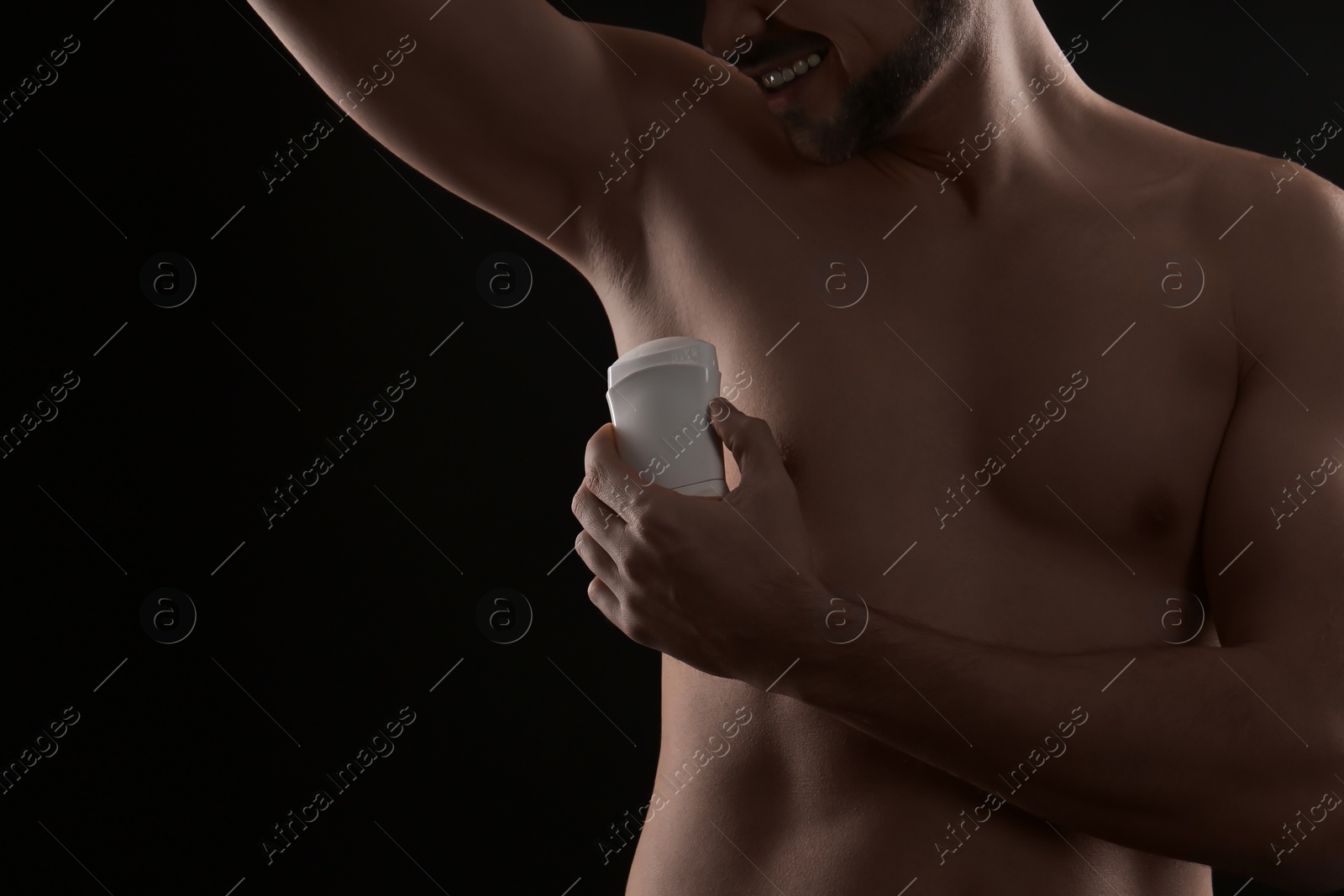 Photo of Man applying deodorant on black background, closeup. Space for text