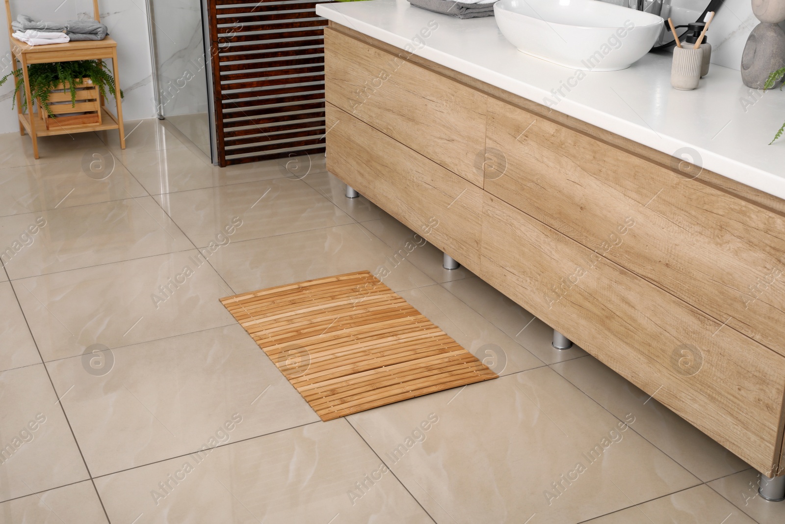 Photo of Wooden mat on floor in bathroom. Interior design