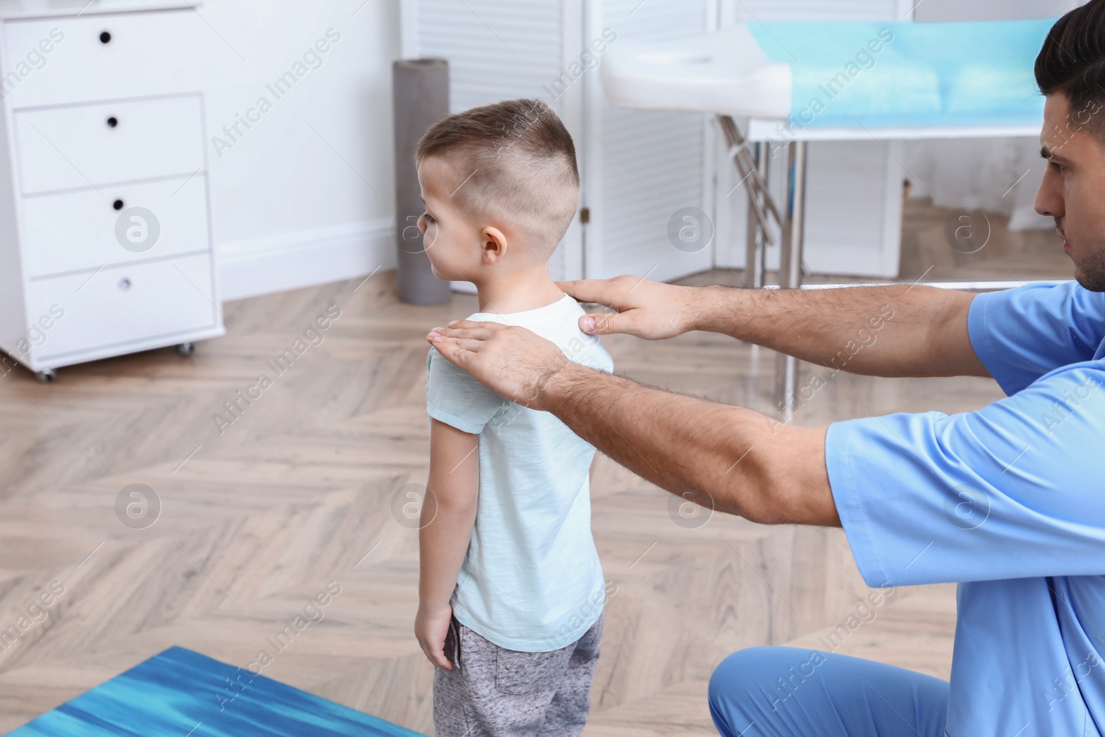 Photo of Orthopedist examining child in clinic. Scoliosis treatment