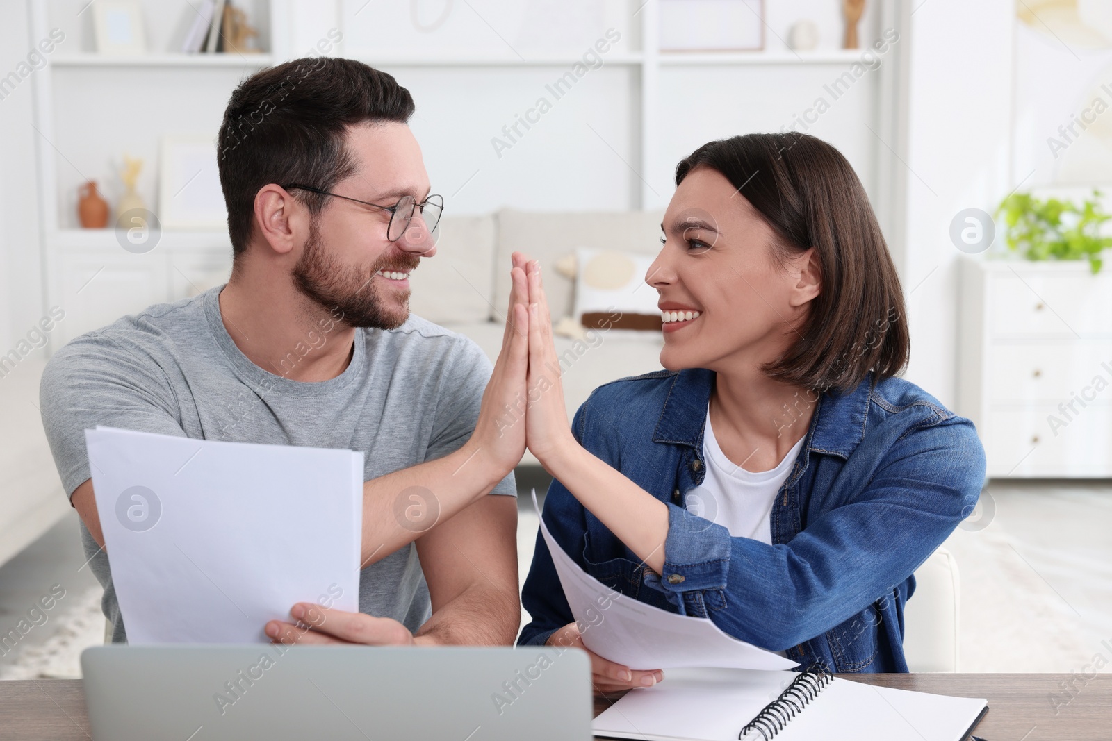 Photo of Young couple with papers discussing pension plan at wooden table indoors