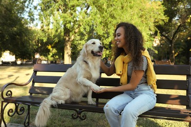 Photo of Young African-American woman and her Golden Retriever dog on bench in park