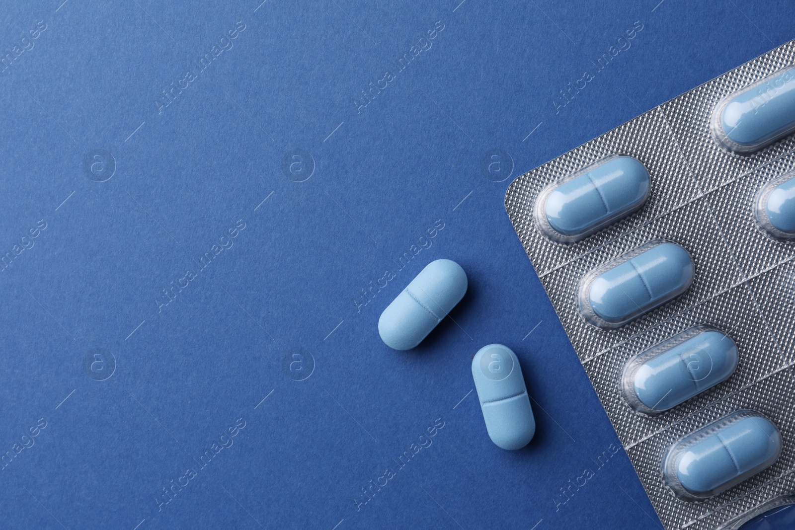 Photo of Pills and space for text on blue background, top view. Potency problem