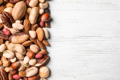 Organic mixed nuts on white wooden background, top view with space for text