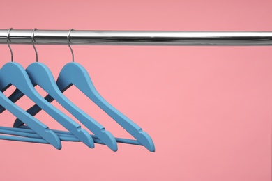 Photo of Empty clothes hangers on metal rail against color background. Space for text