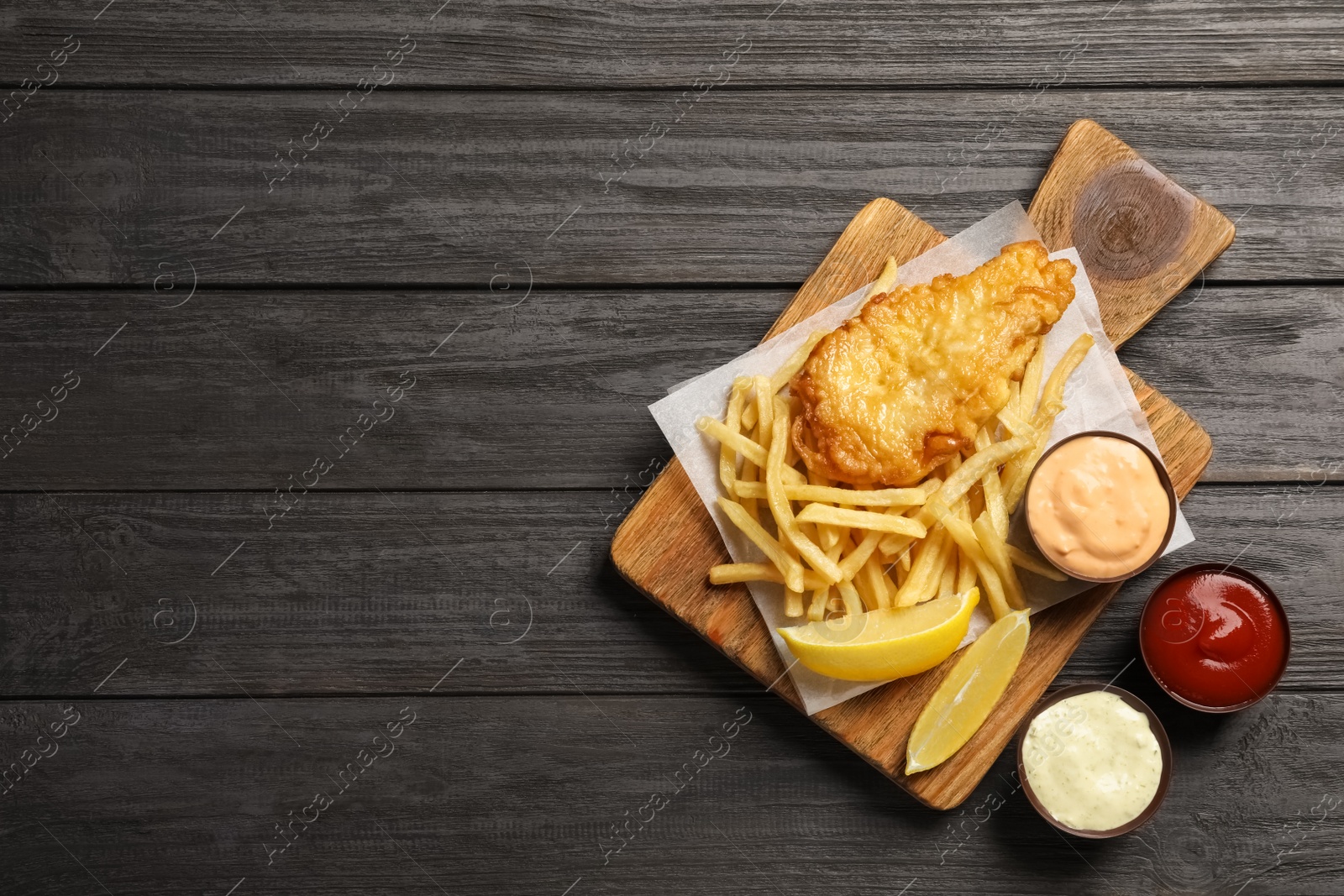 Photo of British traditional fish and potato chips on wooden background, top view with space for text