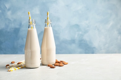 Bottles with almond milk and nuts on light table
