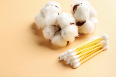 Cotton swabs and flowers on color background, closeup. Space for text