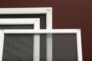 Photo of Set of window screens near brown wall, closeup