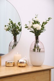 Photo of Beautiful flowers and burning candles on wooden dressing table indoors