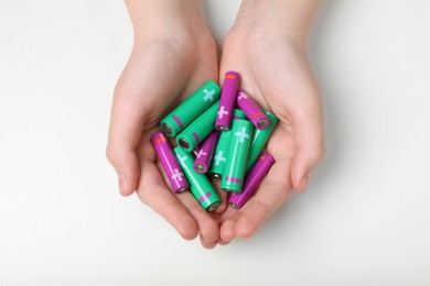 Photo of Woman holding many different batteries on white background, top view