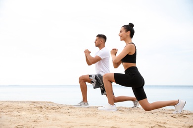 Photo of Couple doing exercise together on beach, space for text. Body training