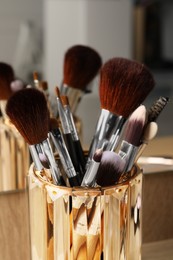 Set of professional makeup brushes near mirror on wooden table, closeup