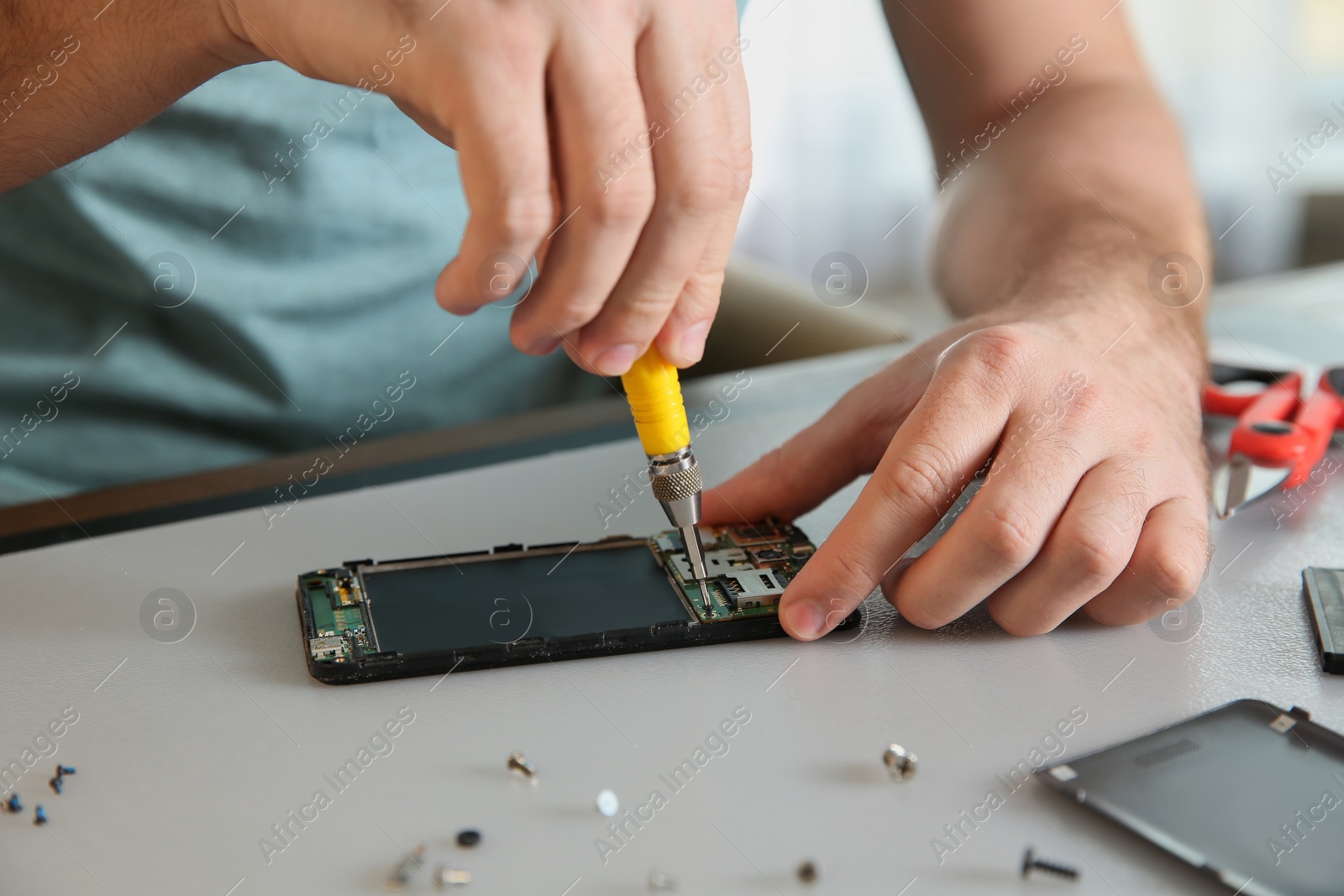 Photo of Technician repairing mobile phone at table, closeup