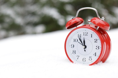 Photo of Red alarm clock on white snow outdoors. Space for text