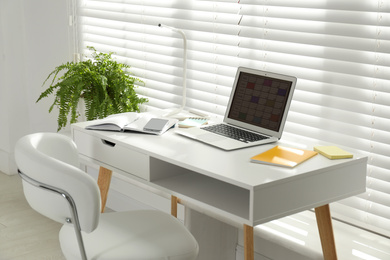 Modern laptop with calendar app at table in office