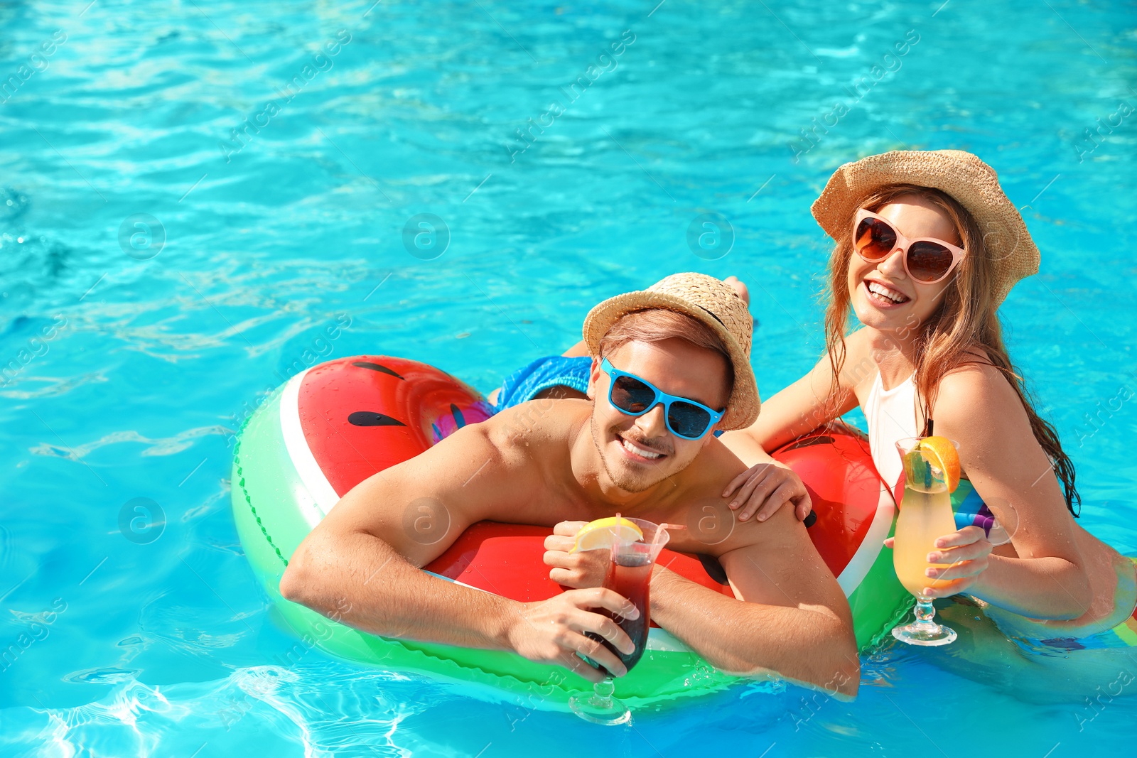 Photo of Young couple with cocktails in pool on sunny day