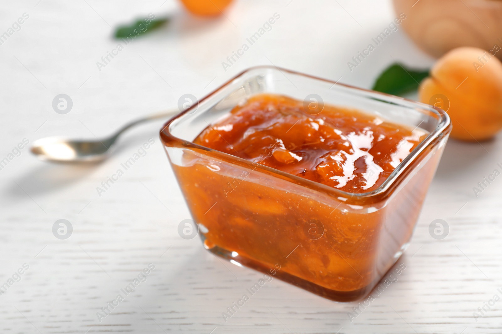 Photo of Bowl with tasty apricot jam on table