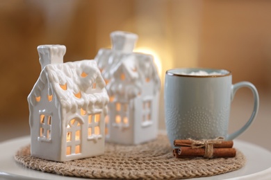 Composition with house shaped candle holder on white table against blurred background. Christmas decoration