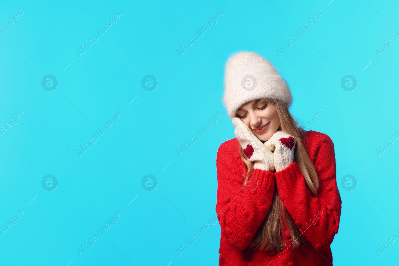 Photo of Portrait of emotional young woman in stylish hat, sweater and mittens on color background, space for text. Winter atmosphere