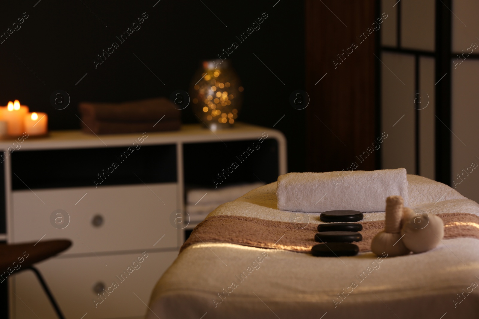 Photo of Herbal compresses and stones on massage table in spa salon. Space for text