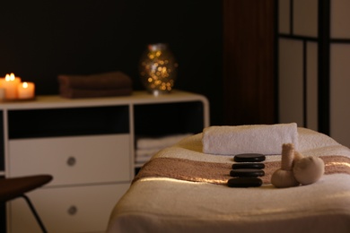 Herbal compresses and stones on massage table in spa salon. Space for text