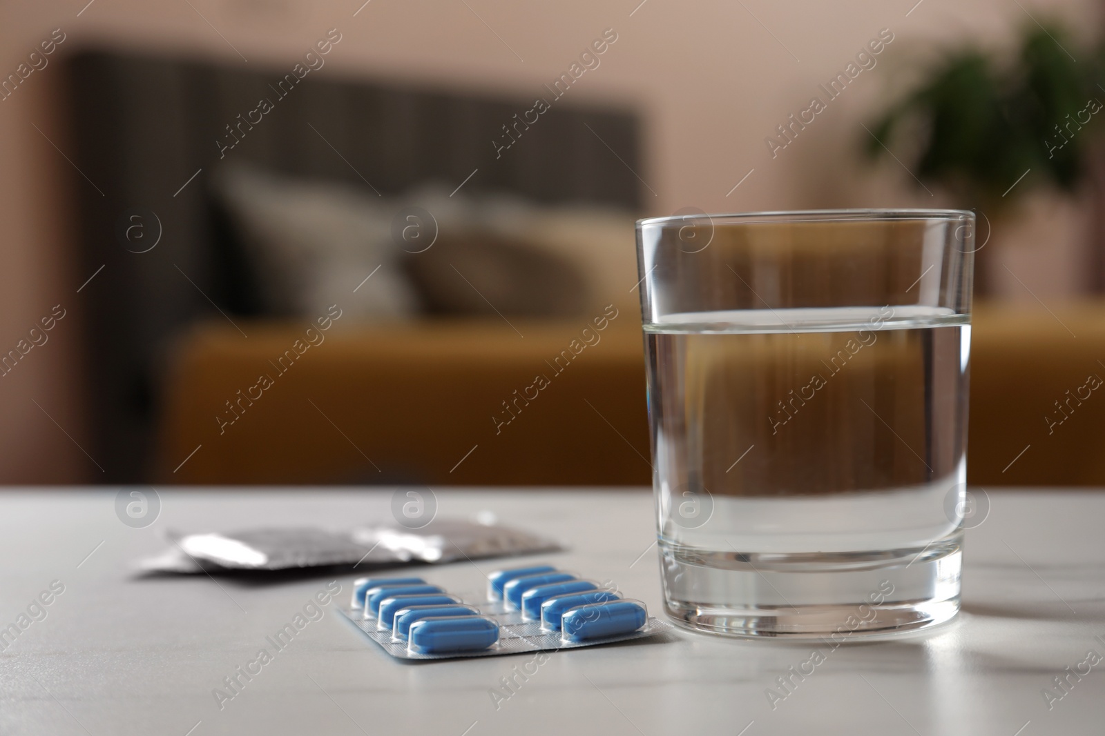 Photo of Glass of water, condoms and pills on white table indoors, space for text. Potency problem concept