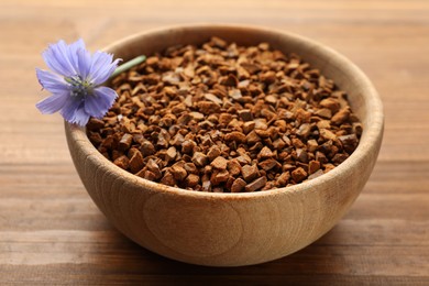 Photo of Bowl of chicory granules with flower on wooden table