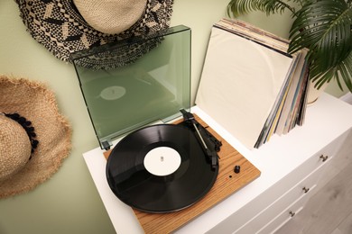 Photo of Turntable and collection of vinyl records on white dresser indoors
