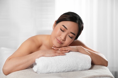 Photo of Beautiful Asian woman lying on massage table in spa salon