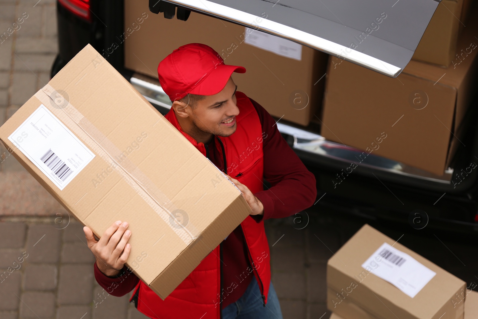 Photo of Courier with parcel near delivery van outdoors, above view