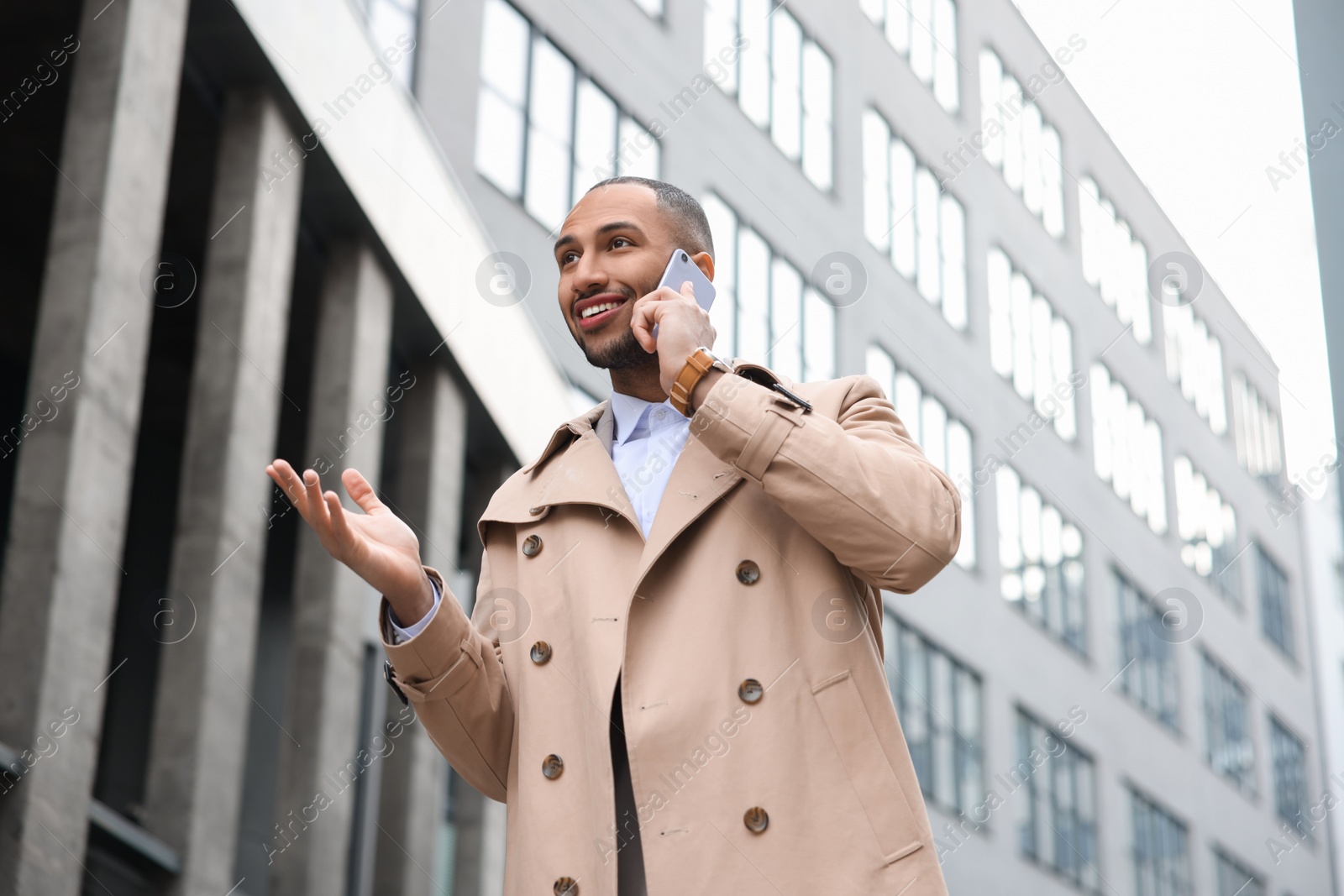 Photo of Happy man talking on smartphone outdoors. Lawyer, businessman, accountant or manager